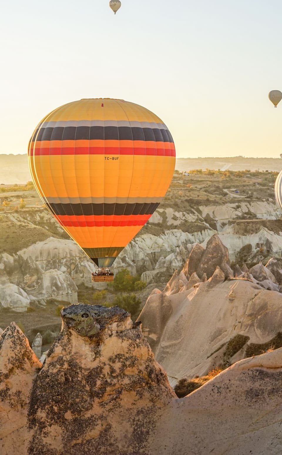 A striped hot air balloon rising over the fairy chimneys at sunrise