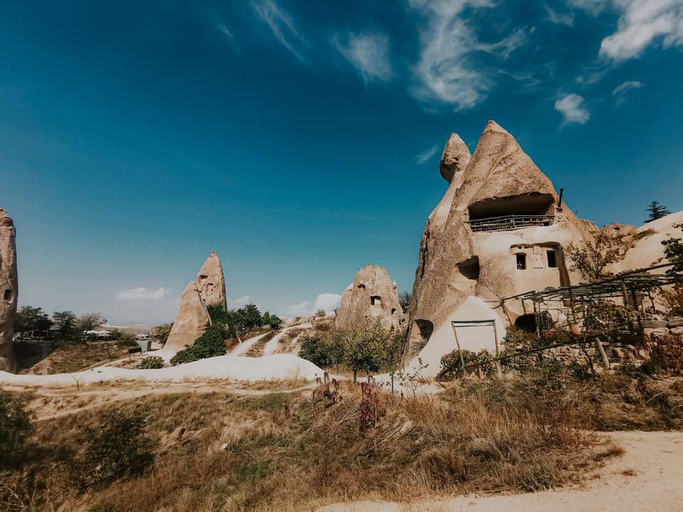 Cave houses carved into rock cones under a blue sky